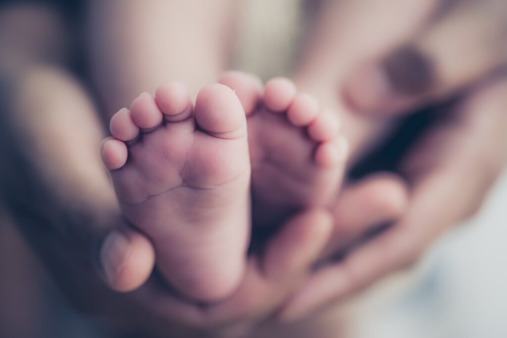 Feet of a newborn baby in the hands of parents. Happy Family onc